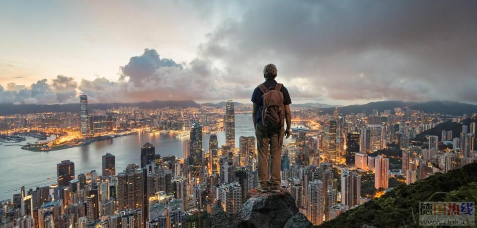 A-man-standing-on-a-rock-overlooking-hong-kong-skyline-at-dawn-from-Victoria-Pe.jpg