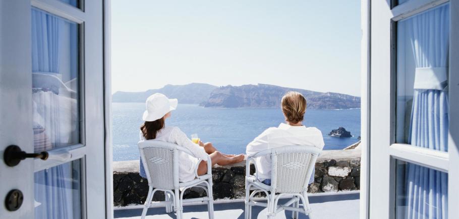 Couple-sitting-on-balcony-overlooking-ocean-view-through-doorway.jpeg