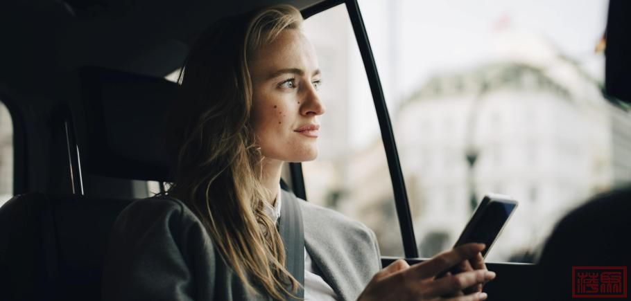 Contemplating-female-entrepreneur-with-smart-phone-looking-through-window-while.jpeg